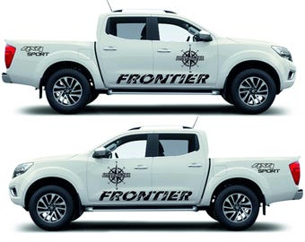 May include: Two white pickup trucks with black accents. Each truck has the words "FRONTIER" and "ADVENTURE" with a compass graphic on the side. The rear of the truck has the words "4x4 SPORT".