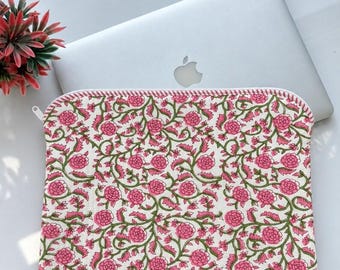 May include: A rectangular laptop sleeve featuring a white fabric base with a repeating pattern of pink flowers and green vines. The sleeve has a white zip closure with a thin pink and white striped trim along the top edge of the fabric.