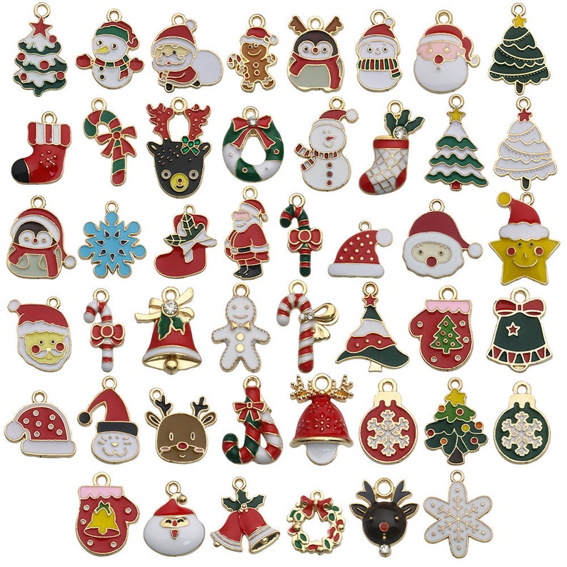 May include: Assortment of gold-tone Christmas charm pendants with enamel details.  The charms feature various holiday themes, including Santa Claus, reindeer, snowmen, candy canes, Christmas trees, and ornaments.