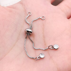 K&ouml;nnte beinhalten: Silbernes Kettenarmband mit einem Schiebeverschluss und zwei kleinen klaren Kristall-Akzenten.