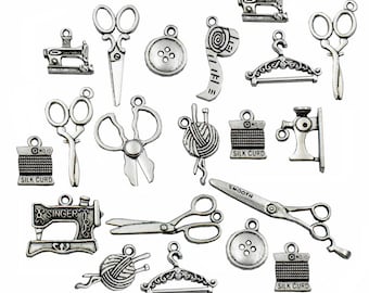 Puede incluir: Una colección de 16 abalorios de metal plateados con temas de costura y artesanía. Los abalorios incluyen máquinas de coser, tijeras, carretes de hilo, botones y una cinta métrica.