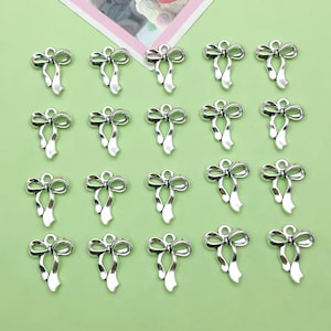 May include: Twenty silver-toned bow charms with a loop at the top for attaching to jewelry or crafts.