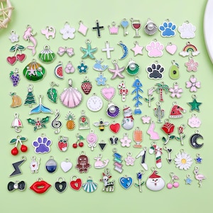 Peut inclure: Une collection de breloques en émail colorées de différentes formes, dont des fleurs, des animaux et des symboles. Les breloques sont dans des tons de rose, bleu, vert et rouge, avec des attaches en métal argenté. Idéal pour la création de bijoux et l'artisanat.