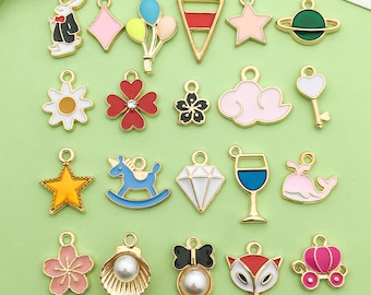 May include: Assortment of 20 colorful enamel charms with various designs, including a rabbit, a star, a heart, a cloud, a diamond, a wine glass, a whale, a unicorn, a flower, a balloon, a shell, a bow, a fox, a carriage, and a key. The charms are made of metal and have a gold finish.
