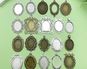 May include: A collection of ornate, oval-shaped pendant trays in various metallic finishes, including silver, bronze, and antique gold. The trays feature decorative filigree and bezel settings, perfect for crafting custom jewelry or pendants. The background is a light green.