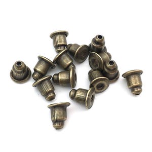 May include: A group of 14 antique gold-toned metal caps for jewelry making. The caps are round with a small hole in the center and a raised lip around the edge.