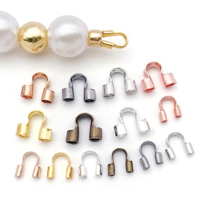 May include: An assortment of jewelry findings, including crimp end caps in various metallic finishes. The caps are in gold, silver, bronze, and rose gold tones. A pearl bead strand with a gold clasp is also visible.