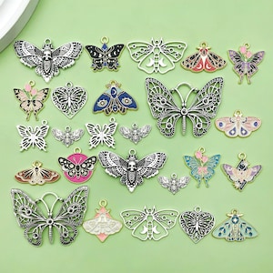 May include: Assortment of silver and enamel butterfly charms with various designs, including floral, celestial, and geometric patterns. The charms are perfect for jewellery making, scrapbooking, and other craft projects.