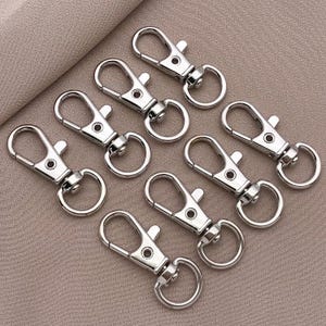 May include: A set of eight silver keychains with a simple, classic design. Each keychain features a sturdy, durable metal loop and a secure clasp.