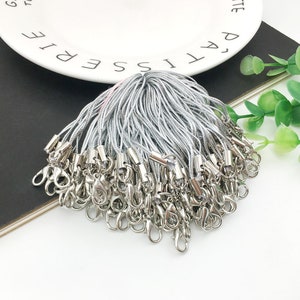 Op de afbeelding: Een stapel zilverkleurige sleutelhangers met een zilveren koord en een zilveren karabijnhaak.