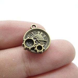 Peut inclure: Un pendentif de couleur bronze avec un cadran d'horloge avec des chiffres romains et des engrenages. Le pendentif a une boucle en haut pour l'attacher à une chaîne ou un cordon.