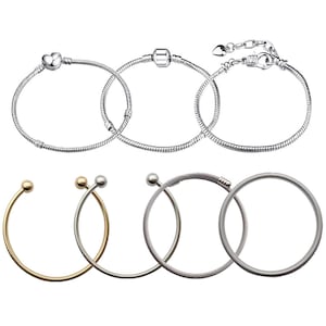 May include: A set of six silver and gold bracelets. Three silver bracelets are chain link style with a heart charm, a bead charm, and a clasp. Three gold bracelets are bangle style with a smooth finish, a twisted finish, and a cable finish.