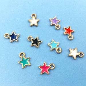 Puede incluir: Surtido de diez abalorios de estrella de tono dorado con pintura de esmalte en varios colores, incluyendo blanco, morado, rojo, azul, negro, turquesa y rosa.