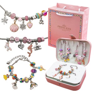 May include: A set of four charm bracelets presented in a pink gift box. The bracelets feature silver chains with colourful charms, including a unicorn, mermaid, camera, heart, snowflake, seashell, rainbow, and cloud. The box has the word "Princess" printed on it.