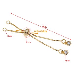 K&ouml;nnte beinhalten: Goldfarbener verstellbarer Kettenverl&auml;ngerer mit zwei kleinen, klaren Kristallanh&auml;ngern. Der Verl&auml;ngerer ist 5 cm lang und hat eine 7 mm Perle in der Mitte. Die Anh&auml;nger haben einen Durchmesser von 4 mm.