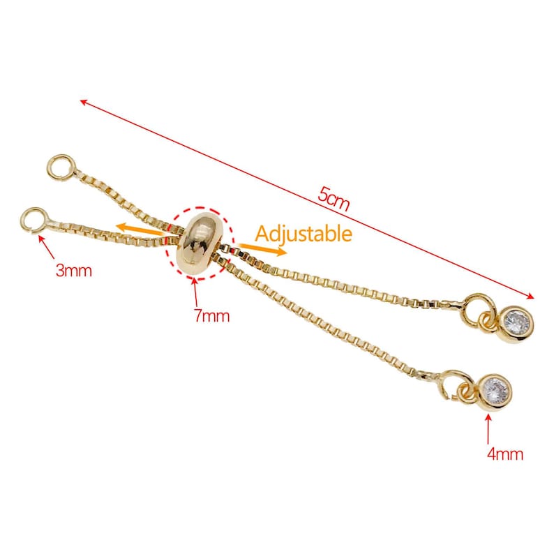 K&ouml;nnte beinhalten: Goldfarbener verstellbarer Kettenverl&auml;ngerer mit zwei kleinen, klaren Kristallanh&auml;ngern. Der Verl&auml;ngerer ist 5 cm lang und hat eine 7 mm Perle in der Mitte. Die Anh&auml;nger haben einen Durchmesser von 4 mm.