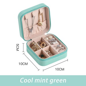 May include: A small, square, mint green jewelry box with a zipper closure. The box has six compartments for storing rings, earrings, and necklaces. The box measures 10 cm by 10 cm by 5 cm.