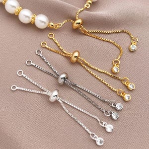 May include: Three silver and gold adjustable chain bracelets with clear crystal beads. Each bracelet has a sliding bead to adjust the length.