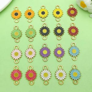 May include: A collection of colorful sunflower charms with gold-tone connectors. The charms feature various colors, including yellow, orange, red, pink, purple, green, white, and blue, with black or yellow centers. These charms are ideal for jewelry making.