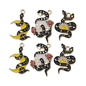 Può includere: Sei ciondoli in metallo dorato con serpenti neri con diversi design. I ciondoli includono un serpente con una luna crescente, un serpente con un teschio, un serpente con un sole, un serpente con una luna crescente, un serpente con un teschio e un serpente con un sole.