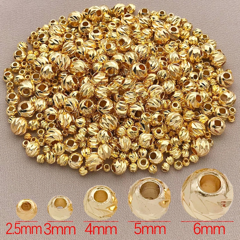 May include: A selection of gold-coloured metal beads, varying in size from 2.5mm to 6mm. The beads have textured surfaces, ideal for jewellery making and crafts. The image includes text indicating the bead sizes in millimetres.