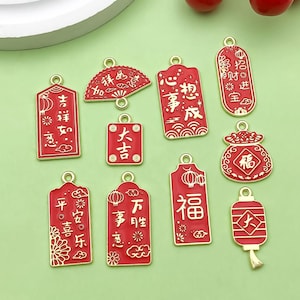 Pode incluir: Uma coleção de amuletos vermelhos e dourados do Ano Novo Chinês com várias formas e caracteres chineses. Os amuletos incluem lanternas, leques e etiquetas retangulares com frases como "Boa sorte" e "Prosperidade".