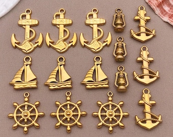May include: A collection of gold-colored nautical charms, including anchors, sailboats, ship wheels, and lanterns. The charms are arranged on a neutral-toned surface, showcasing their intricate details and maritime theme.