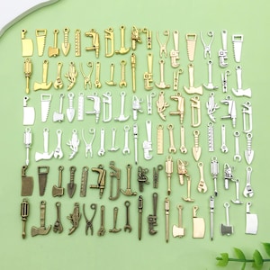 May include: A large collection of silver and gold-toned metal charms shaped like various tools, including wrenches, hammers, saws, and screwdrivers.