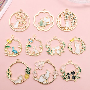 May include: Nine gold-tone metal charms featuring different cat designs. Each charm has a circular frame with a different floral or geometric design. The charms are perfect for adding a touch of whimsy to jewelry or crafts.
