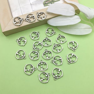 May include: A collection of silver-toned metal charms featuring a cat silhouette inside a circle with stars. The charms have a loop at the top for attaching to jewelry or other crafts.
