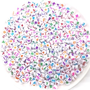 May include: A large pile of white plastic alphabet beads with colorful letters and star accents.
