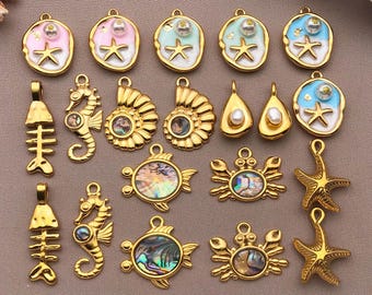 May include: A collection of gold-toned pendants and charms with a nautical theme. Designs include starfish, seahorses, fish skeletons, shells, and crabs. Some charms feature iridescent abalone shells, pearls, and pastel enamel accents.