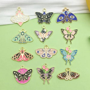 Puede incluir: Surtido de 12 abalorios de mariposa de metal dorado con pintura de esmalte en varios colores y diseños. Los abalorios presentan mariposas con detalles florales, detalles de luna y estrellas y patrones geométricos.