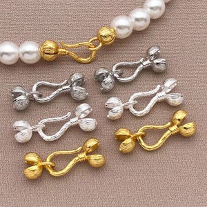 May include: Assortment of silver and gold tone metal clasps with a coconut design. The clasps are perfect for jewellery making and crafting.