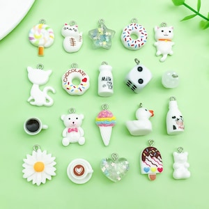 以下が含まれることがあります： ロリポップ、猫、星、ドーナツ、文字入りミルクボトル、サイコロ、コーヒーカップ、テディベア、アイスクリーム、アヒル、デイジー、ハート、アイスキャンディーなど、様々な形の20個の小さなチャームのコレクション。
