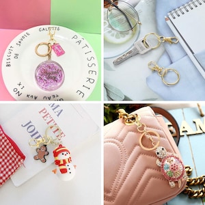 May include: A set of four keychains with different charms. The charms include a pink glitter keychain with the text "Special Day", a snowman and gingerbread man keychain, a gold turtle keychain with colorful rhinestones, and a gold keychain with a round ring.