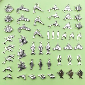 May include: A collection of silver-toned metal charms shaped like fish, dolphins, and crosses. The charms are perfect for jewelry making, scrapbooking, and other craft projects.