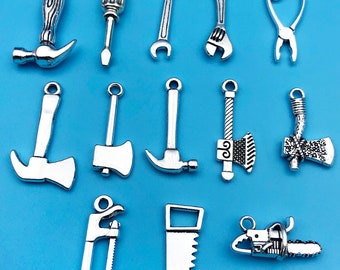 May include: A set of 13 silver-toned metal charms shaped like various tools, including a hammer, axe, wrench, screwdriver, pliers, saw, and chainsaw. The charms are perfect for adding a DIY or construction theme to jewelry or crafts.