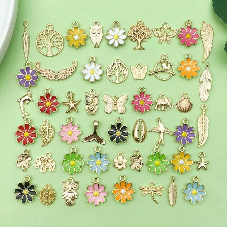 May include: Assortment of gold-tone metal charms with enamel accents. The charms feature various designs, including flowers, animals, and geometric shapes. The charms are perfect for adding a touch of personality to jewelry, keychains, and other crafts.