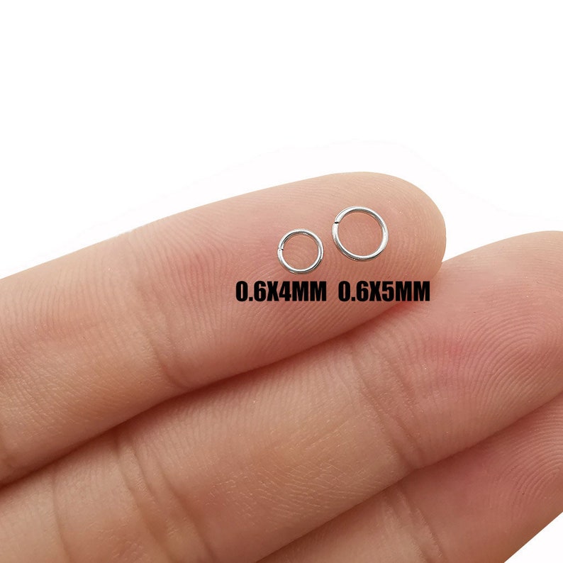 May include: Two silver jump rings, one measuring 0.6x4mm and the other 0.6x5mm, are shown on a finger.