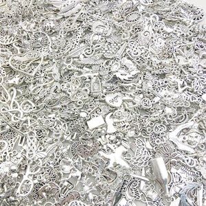 Pu&ograve; includere: Un vasto assortimento di ciondoli in metallo argentato con vari disegni, tra cui cuori, fiori, foglie e forme astratte. I ciondoli sono perfetti per la creazione di gioielli, lo scrapbooking e altri progetti di artigianato.