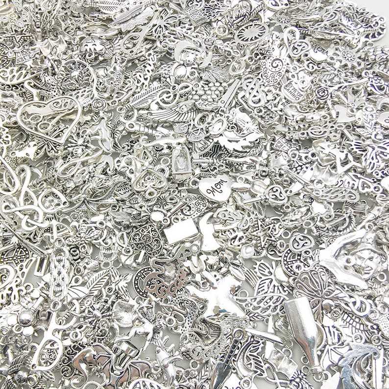 Pu&ograve; includere: Un vasto assortimento di ciondoli in metallo argentato con vari disegni, tra cui cuori, fiori, foglie e forme astratte. I ciondoli sono perfetti per la creazione di gioielli, lo scrapbooking e altri progetti di artigianato.