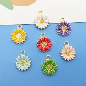 May include: Six gold-tone metal charms shaped like daisies with different colored enamel centers. The charms are white, yellow, purple, red, pink, and green.