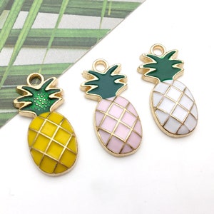 May include: Three colorful pineapple charms. Each charm has a gold-colored outline and a green top. The pineapple bodies are yellow, pink, and white, with a grid pattern. These charms are perfect for jewelry making or other craft projects.