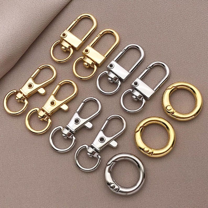May include: Assortment of silver and gold keychains with different styles and shapes.  The keychains include a variety of rings, loops, and swivel clips.