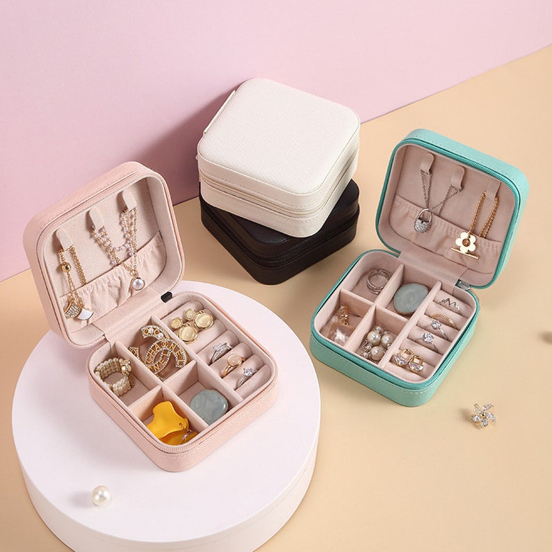 May include: Three different jewelry boxes with compartments for rings, earrings, and necklaces. The boxes are pink, green, and white.