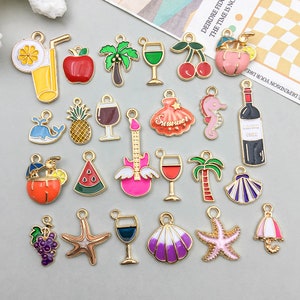 Peut inclure: Une collection de breloques en émail coloré avec des bordures en métal doré. Les motifs comprennent un cocktail, une pomme, un palmier, des verres à vin, des cerises, une guitare rose, un hippocampe, une bouteille de vin et un coquillage.