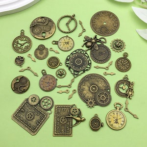 Puede incluir: Surtido de dijes de esfera de reloj de metal dorado antiguo con números romanos y arábigos. Los dijes presentan engranajes, manecillas y otros diseños relacionados con el reloj.