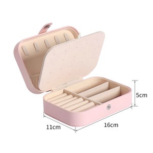 May include: A pink jewellery box with a hinged lid and multiple compartments for storing rings and earrings. The box measures 16cm by 11cm by 5cm.
