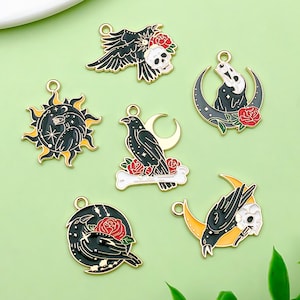 May include: Six black and gold metal charms featuring ravens, skulls, crescent moons, and roses. The charms are perfect for adding a gothic touch to jewelry or crafts.